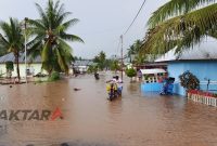Warga melintasi banjir yang merendam Desa Olimohulo, Kabupaten Gorontalo. Pemkab menyebut kapasitas gorong-gorong yang tak lagi memadai menjadi penyebab banjir berulang.(Foto: Ist*)
